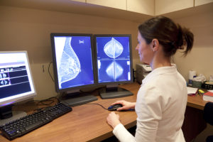 Female radiology technician reviews mammogram.